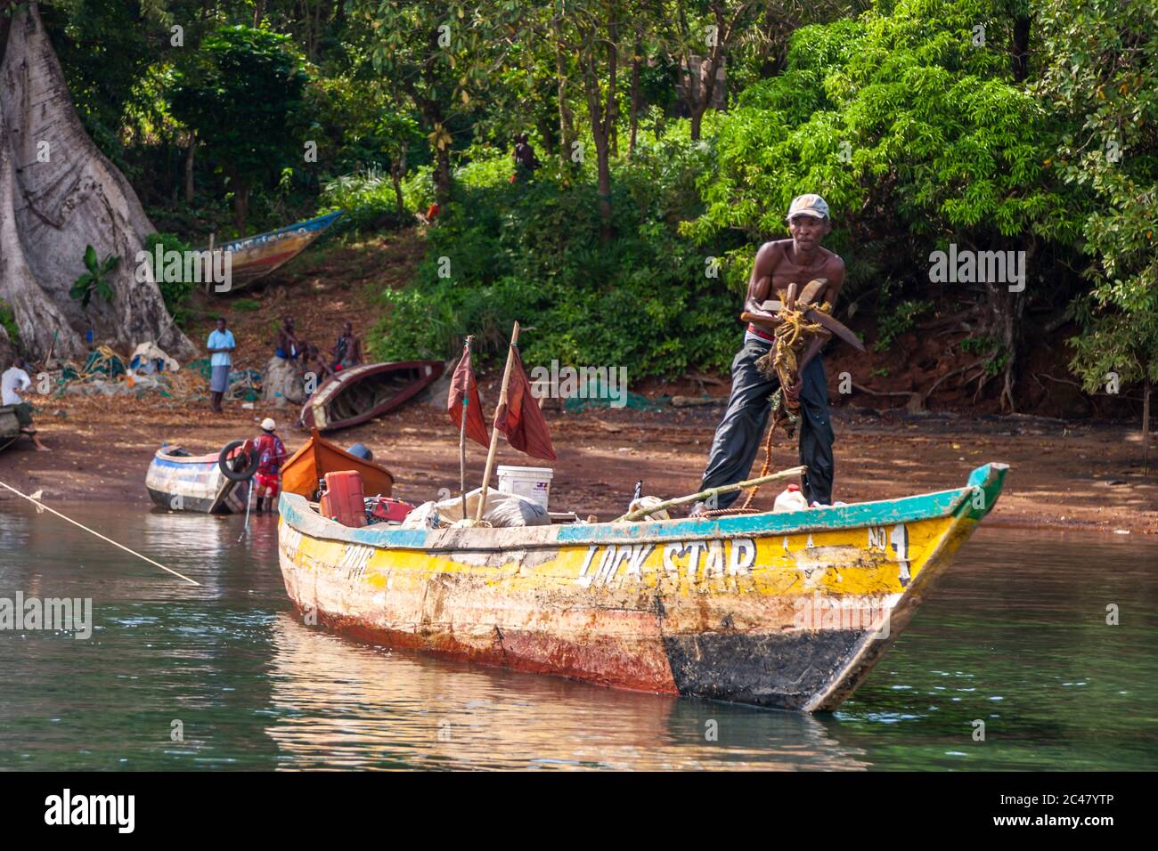 Un pescatore getta l'ancora da una barca chiamata la stella di bloccaggio su Banana Islane, Sierra Leone Foto Stock