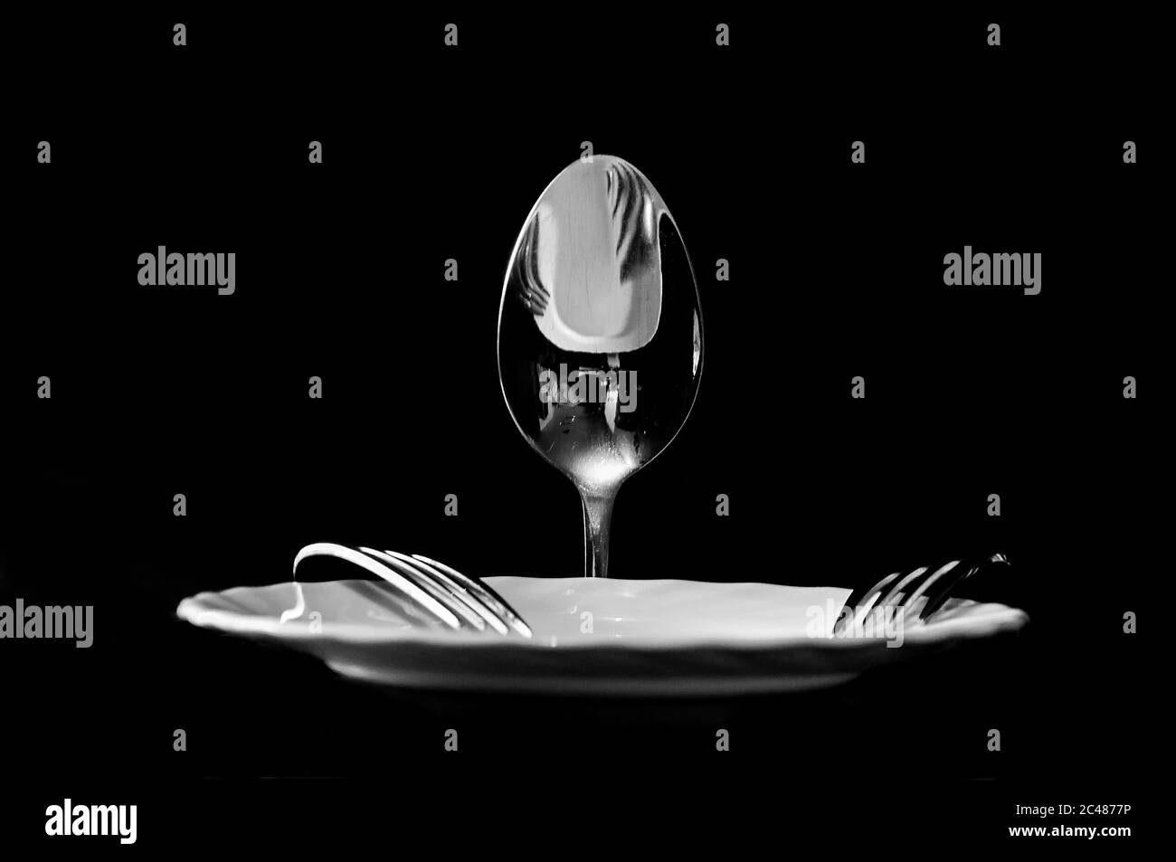 foto di cucchiai e forcelle con un piatto in forma di uomo su sfondo nero Foto Stock