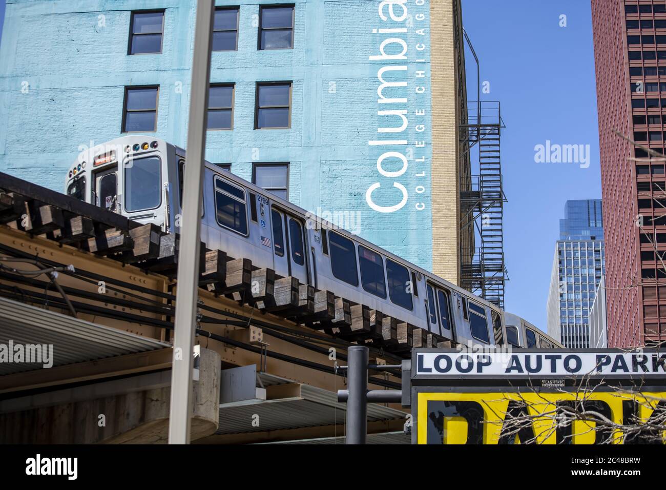 CHICAGO, STATI UNITI - 18 aprile 2020: Il treno CTA passa sopra la testa con il Columbia College Building sullo sfondo in una giornata di sole brillante in th Foto Stock