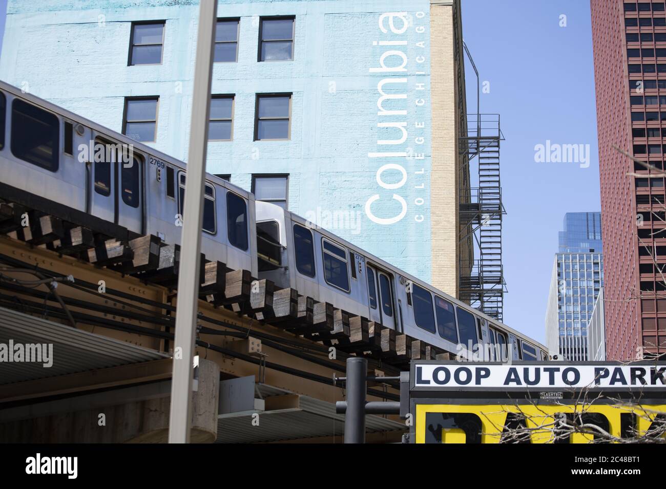CHICAGO, STATI UNITI - 18 aprile 2020: Il treno CTA passa sopra la testa con il Columbia College Building sullo sfondo in una giornata di sole brillante in th Foto Stock