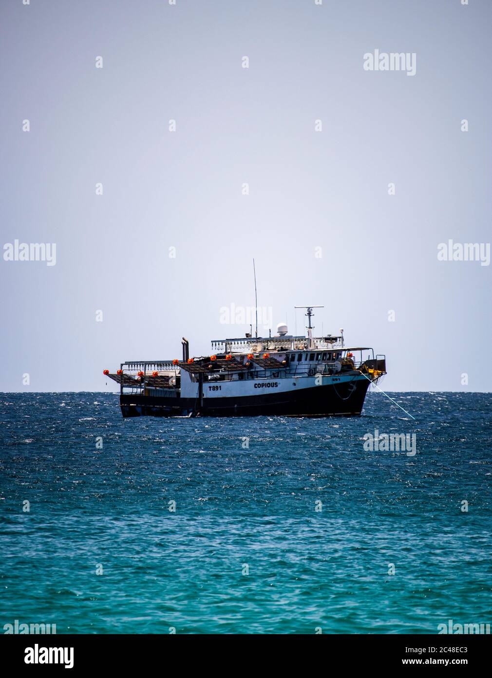 Solitario mare chiatta su un mare tranquillo e vibrante con cieli grigi Foto Stock