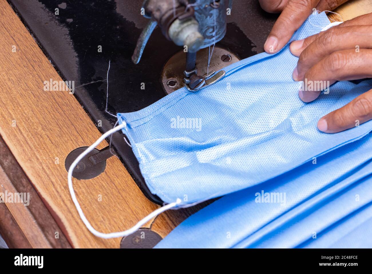 Una maschera facciale da carta da imballaggio sterilizzante su una macchina per cucire. Un prodotto fatto in casa di maschere per proteggere da sporco, smog e virus, chiudere Foto Stock