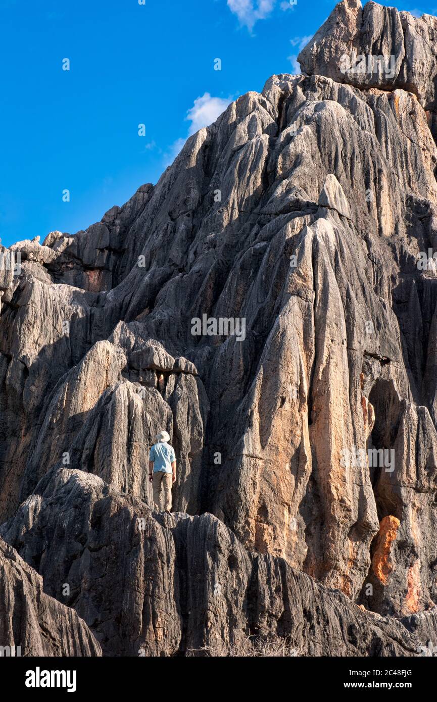 Tourist si erge a metà strada sui bastioni calcarei di una scogliera che guarda in cima e il cielo sopra a Chillagoe in Queensland, Australia. Foto Stock