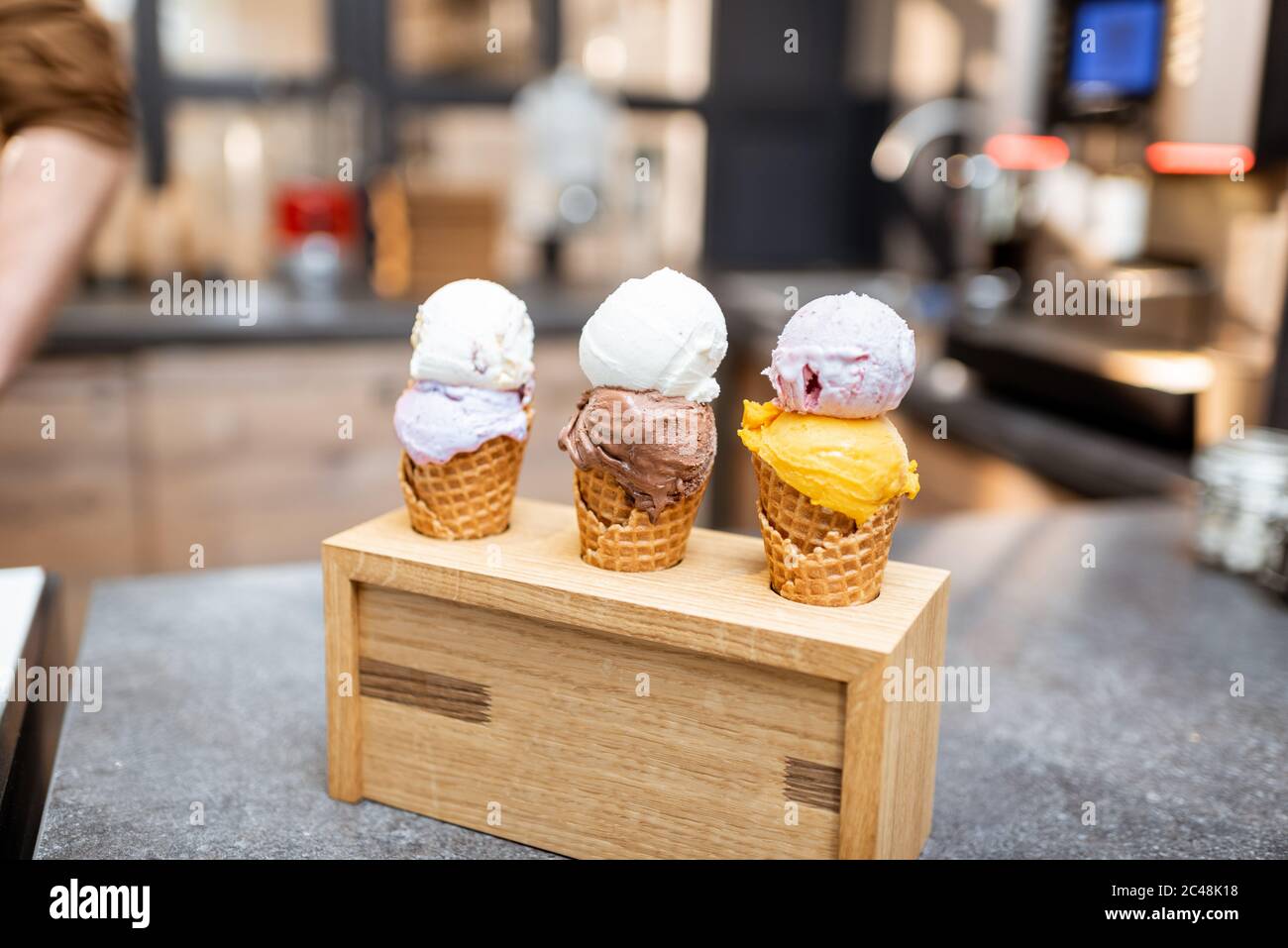 Gelato nel cono del waffle con diversi gusti al banco del negozio, primo piano Foto Stock