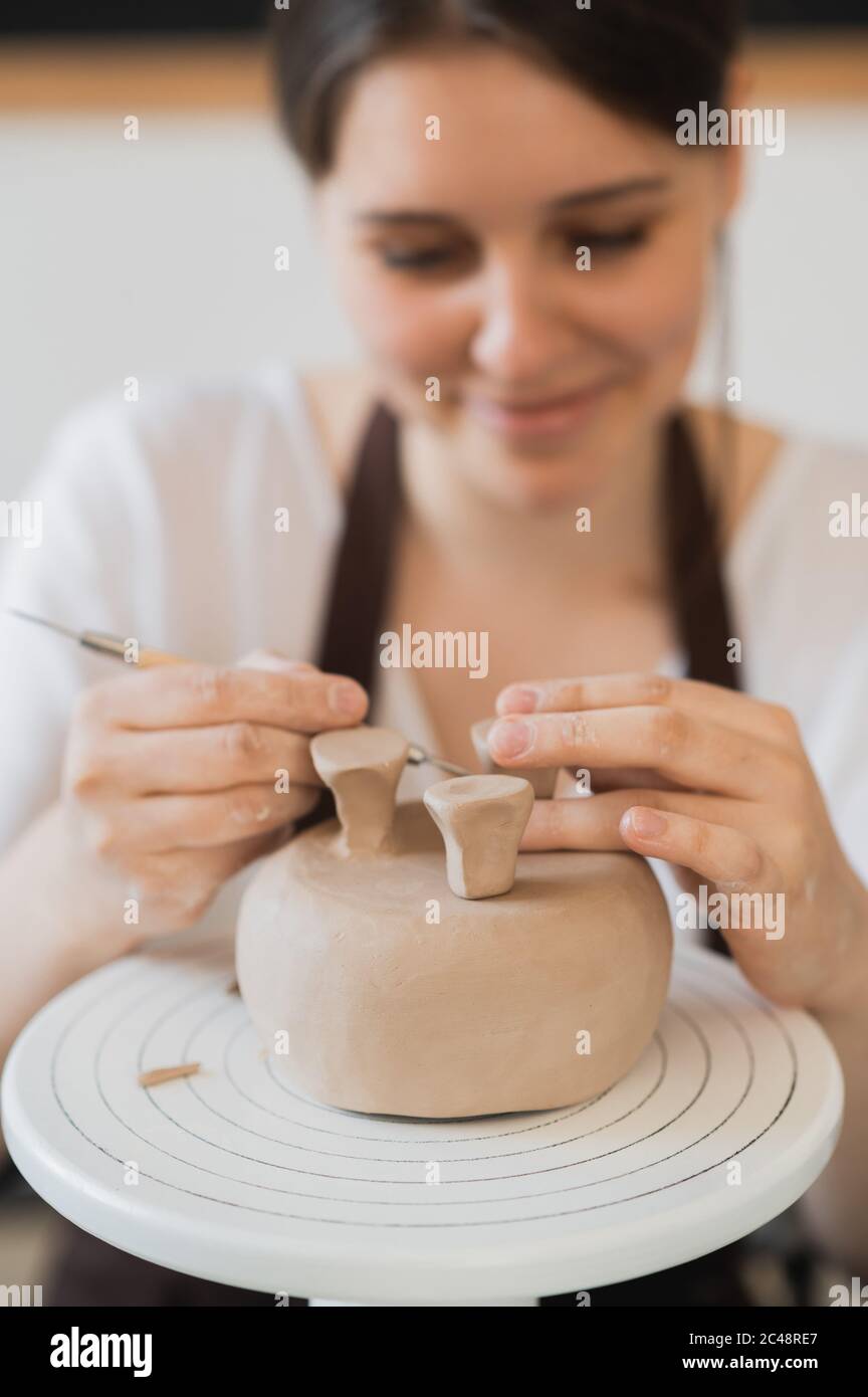 Primo piano di femmina potter che tiene il bastone e facendo ornamento su terracotta. Creta il prodotto di creta di stampaggio principale. Concetto di arte ceramica e hobby. Foto Stock