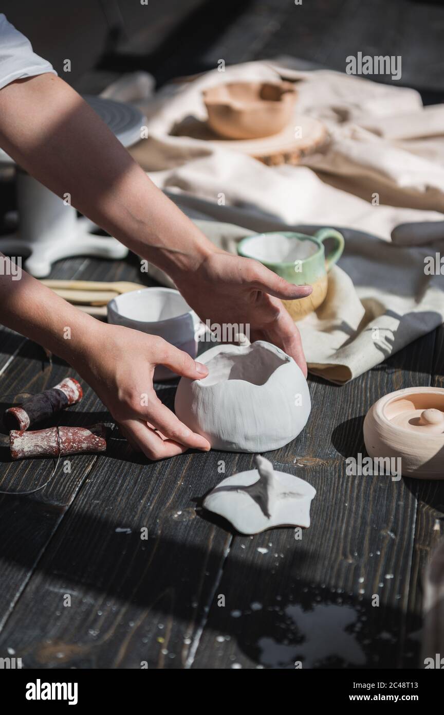 Femmina vasaio che fa piatti di ceramica al suo studio. Processo di lavorazione della vaschetta in ceramica per vetratura. Foto Stock