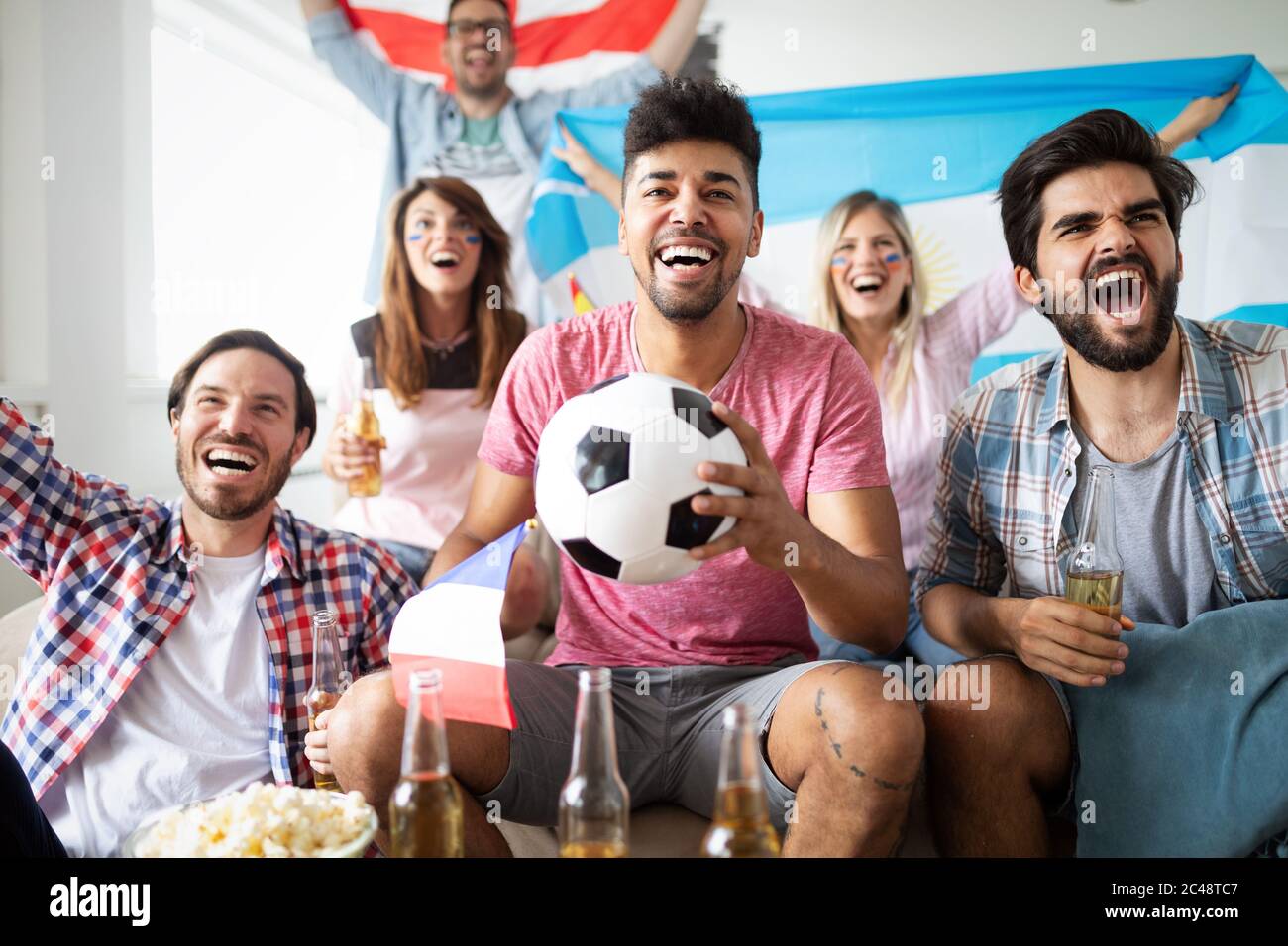 Gruppo felice di giovani amici che guardano la televisione e sostengono il loro team Foto Stock