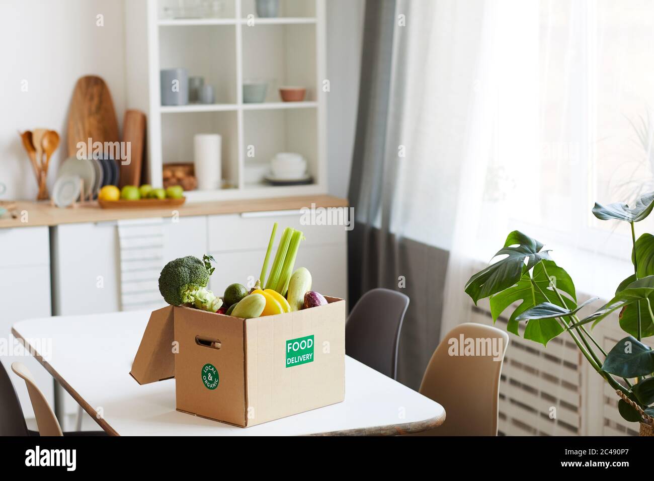 Immagine di verdure fresche in scatola di cartone sul tavolo in cucina domestica Foto Stock