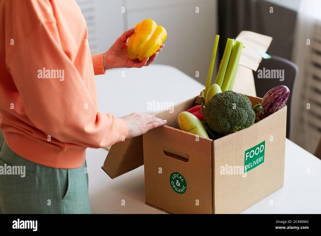 Primo piano di giovane donna che prende verdure fresche fuori dalla scatola in cucina Foto Stock