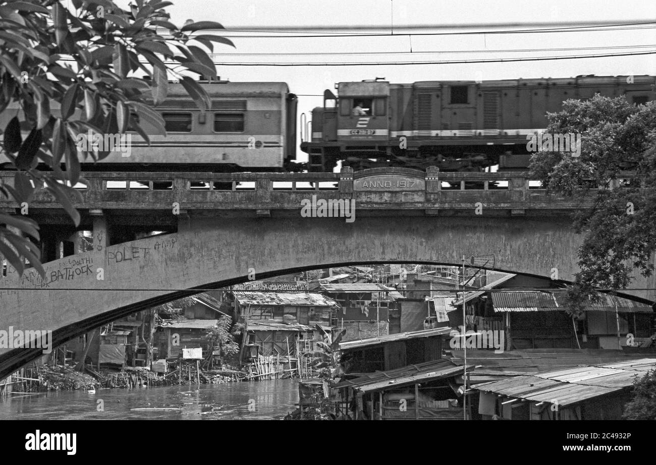 giacarta, dki jakarta/indonesia - 09 dicembre 2002: un treno che attraversa un vecchio ponte ferroviario coloniale di 1917 metri sul fiume ciliwung in kampung melayu Foto Stock