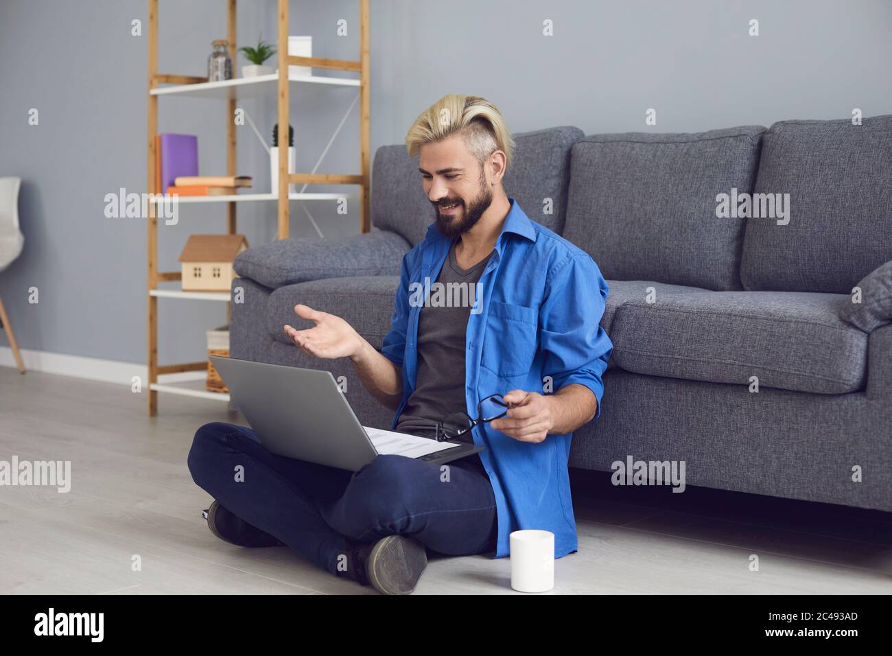 Lavoratore in ufficio che comunica tramite chat video utilizzando un computer portatile in salotto. Buon ragazzo che lavora o studia online da casa Foto Stock