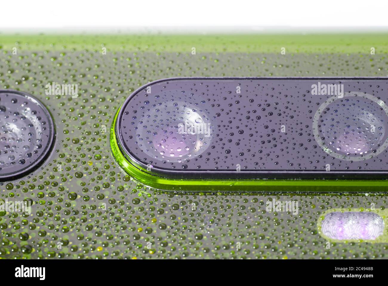 obiettivo verde della fotocamera del telefono coperto da piccole gocce d'acqua - primo piano con messa a fuoco e sfocatura selettive Foto Stock