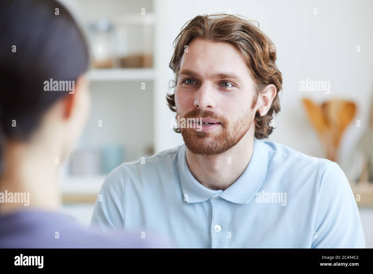 Giovane uomo che parla con la giovane donna mentre si siedono nella stanza Foto Stock