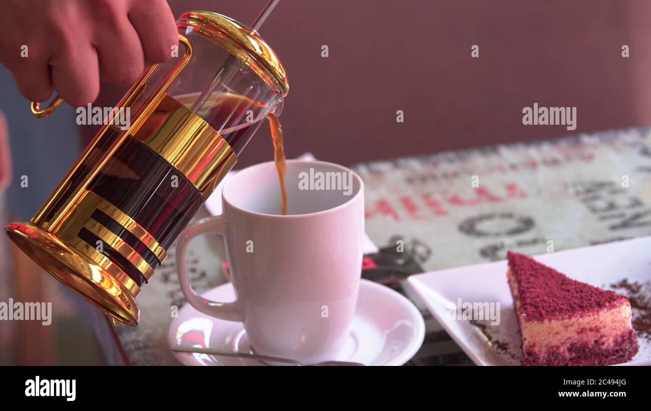 Mani che tengono la caffettiera francese e la tazza bianca Foto Stock