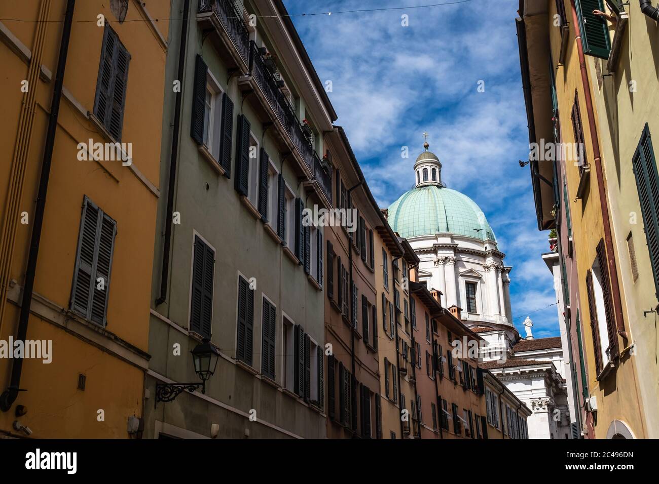 Camminando lungo la strada nel centro storico di Brescia. Vista delle facciate multicolore degli edifici residenziali e della cupola del Duomo nuovo. Foto Stock