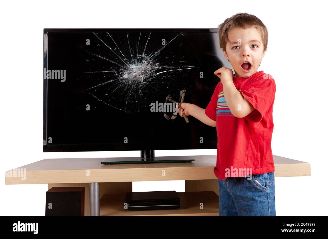 Un ragazzino scioccato che tiene una foto di una trina davanti a un televisore con schermo rotto. Concetto di assicurazione domestica. Studio girato isolato su sfondo bianco. Foto Stock
