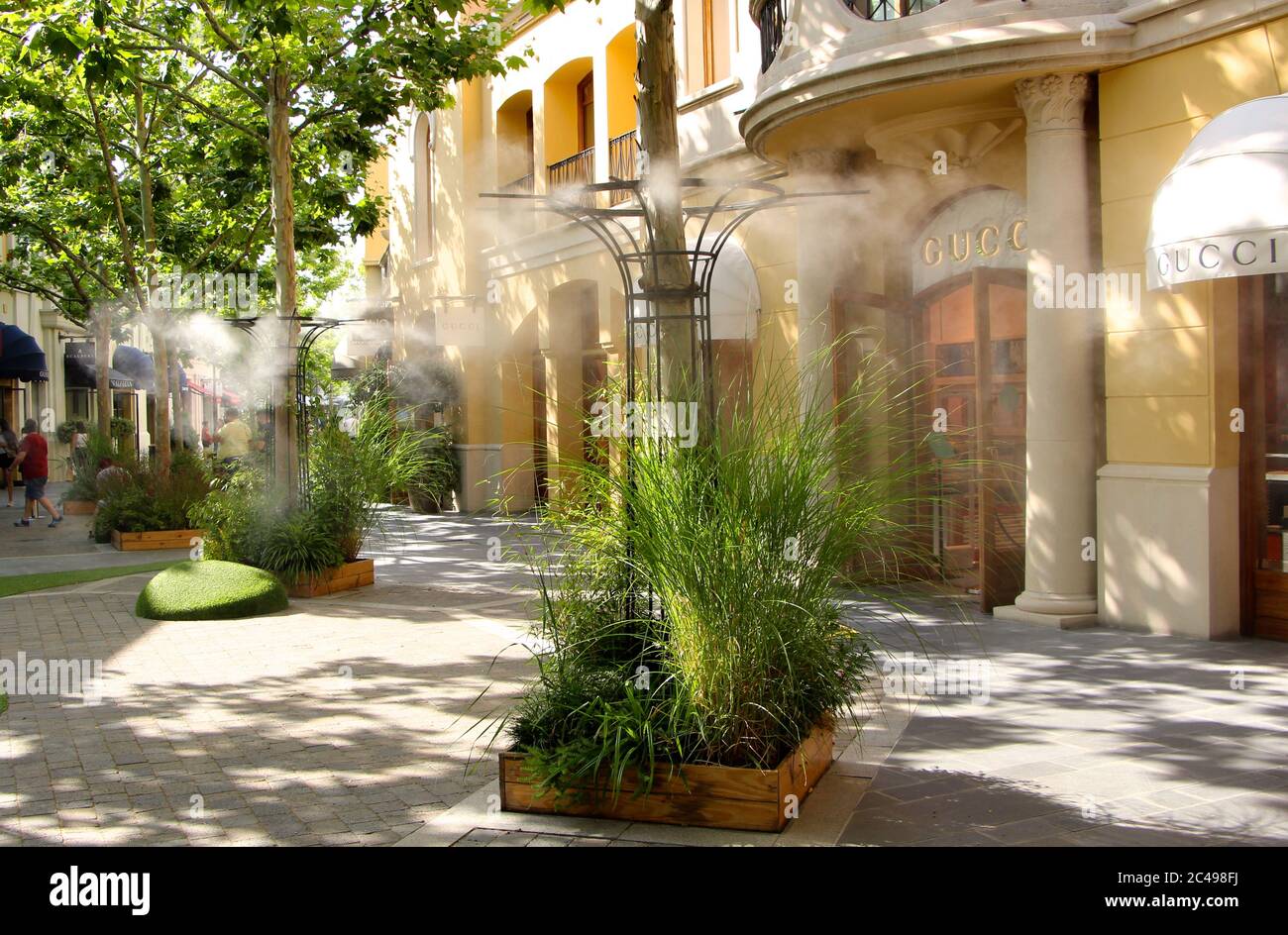 Centro commerciale outlet Las Rozas Madrid Spagna con raffreddamento umidificante Spruzzi d'acqua dalle bocchette nelle zone pedonali vicino a Gucci negozio Foto Stock