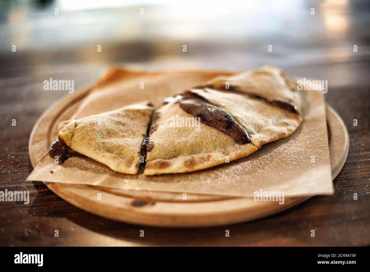 Tortino di mezza luna o di calzone al forno con cioccolato sul tavolo. Calzone al cioccolato su legno dish.dessert. Foto Stock