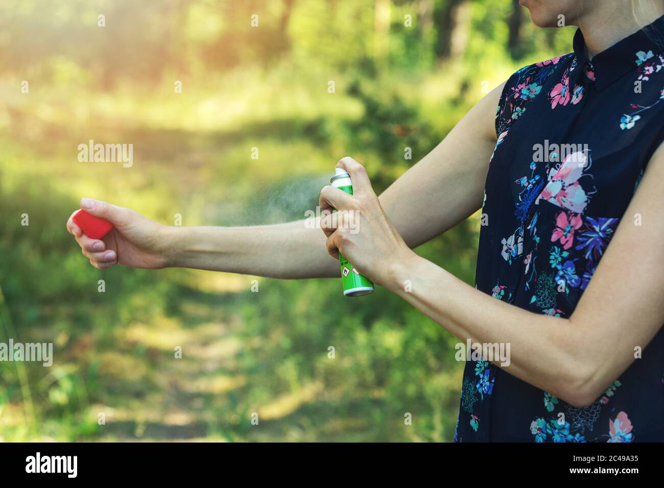donna che spruzzano zanzara e tick repellente sul braccio nella foresta Foto Stock