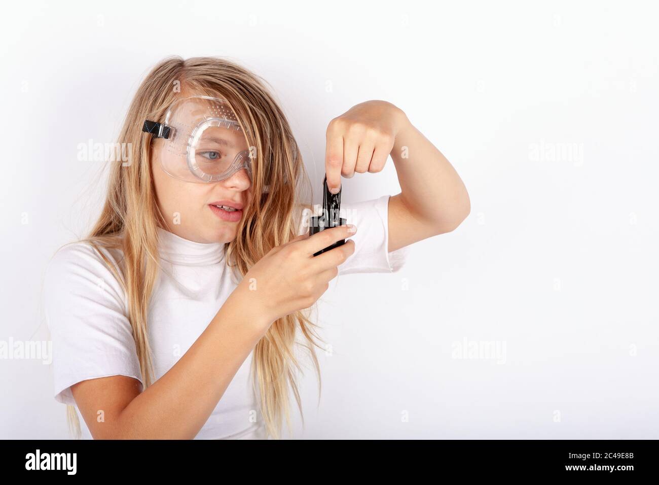 Un piccolo scienziato indossa occhiali di protezione creando un giocattolo scioccatissimo Foto Stock