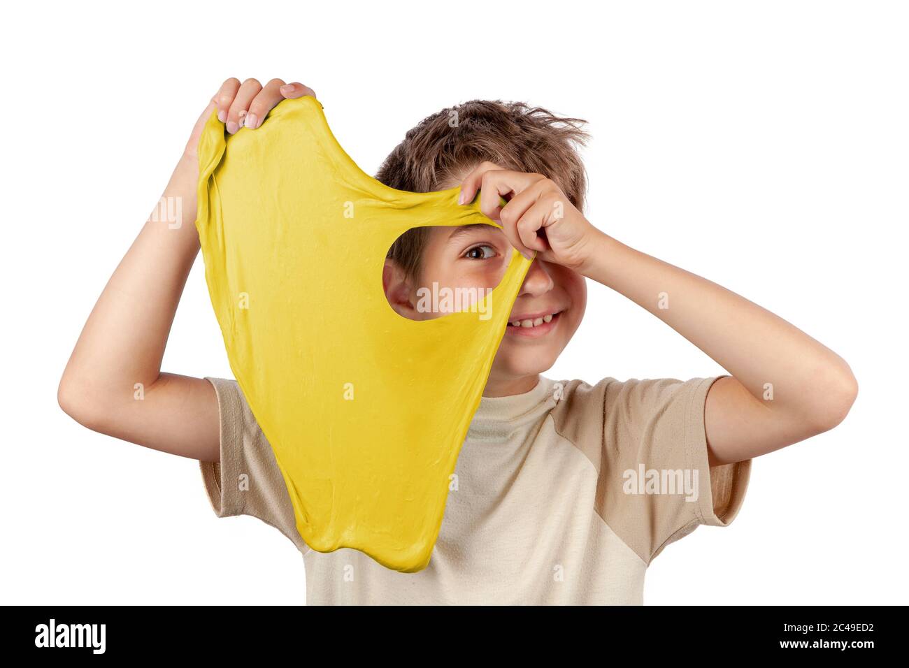 Ragazzo allegro che tiene un giallo melma e guarda attraverso il suo foro. Studio isolato su sfondo bianco. Foto Stock