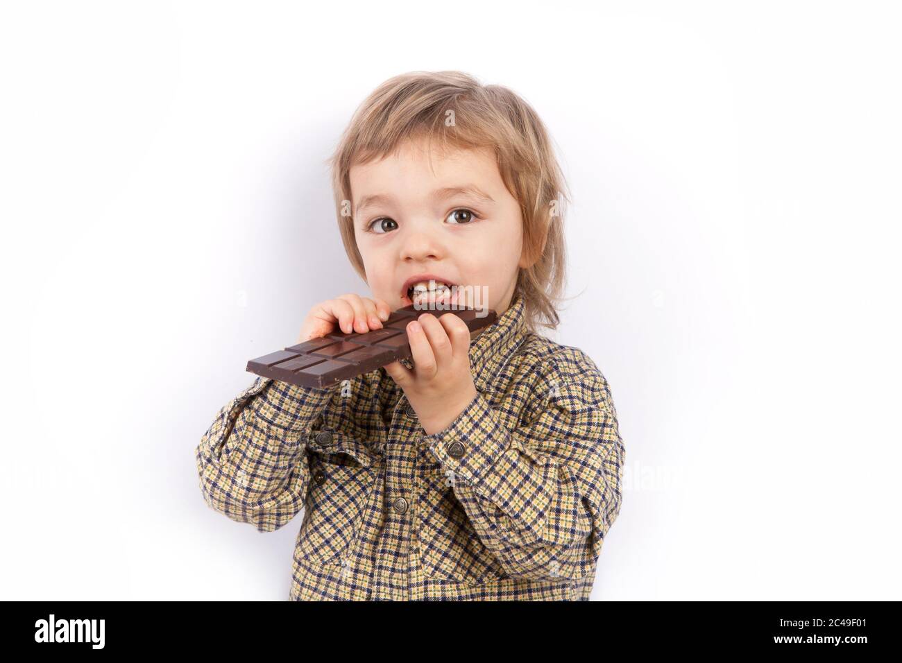 Carino ragazzino che mangia una barretta di cioccolato Foto Stock