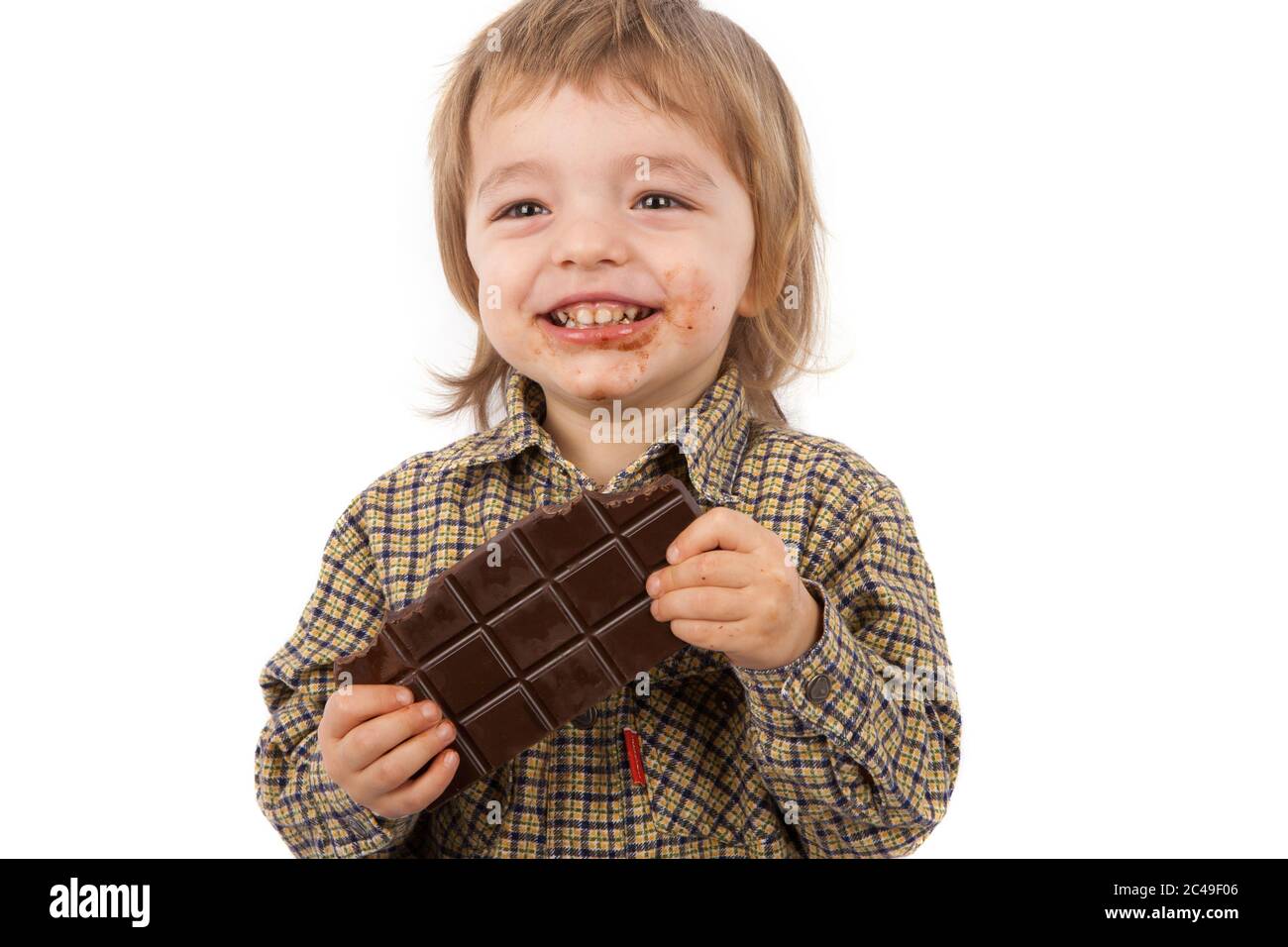 Allegro ragazzo di due anni che mangia una barretta di cioccolato. Isolato su bianco. Foto Stock