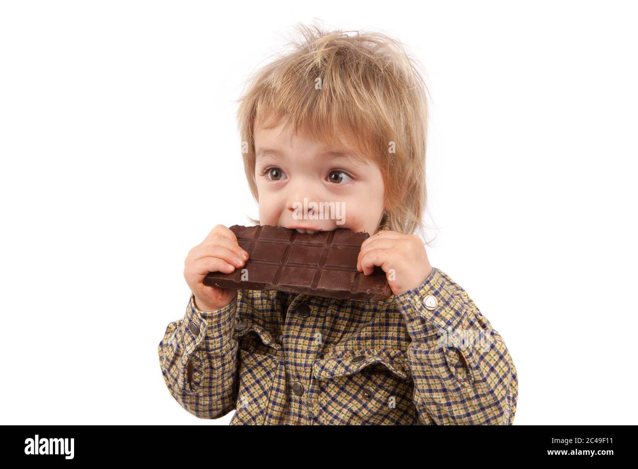 Adorabile bambino di due anni che mangia una barretta di cioccolato. Isolato su sfondo bianco. Foto Stock