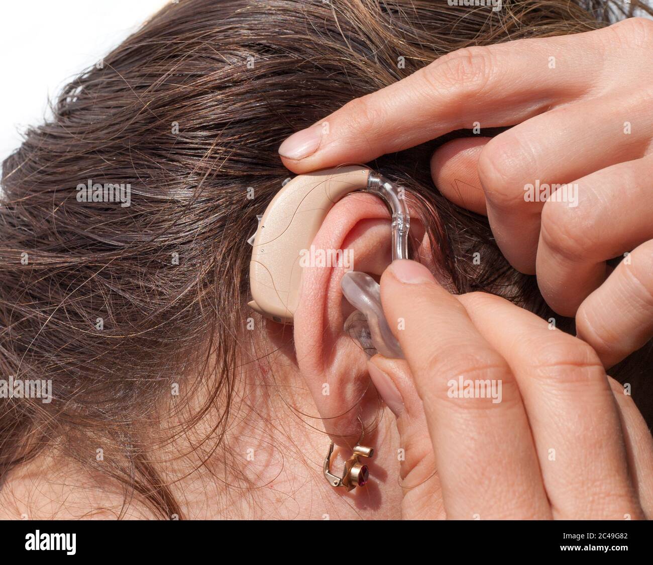 Primo piano di una donna che inserisce un apparecchio acustico nell'orecchio Foto Stock