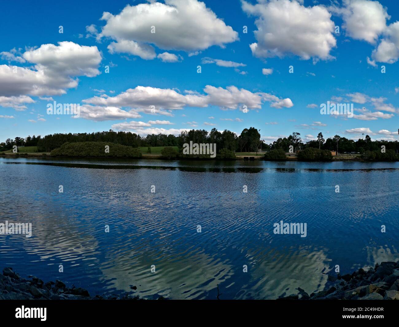 Splendida vista su un fiume con riflessi di cielo blu, nuvole e alberi, fiume Parramatta, Ermington, nuovo Galles del Sud, Australia Foto Stock