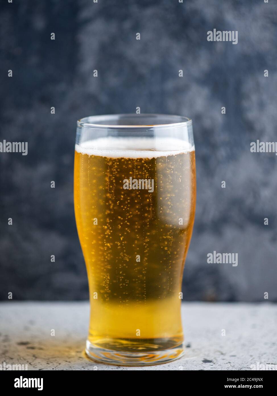 Un bicchiere di birra chiara su sfondo scuro Foto Stock