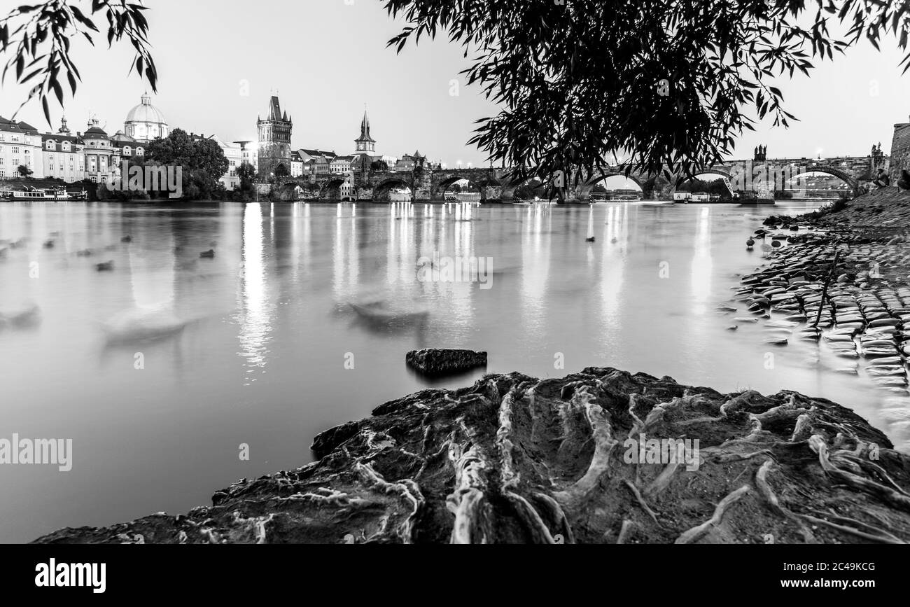 Fiume Moldava e Ponte Carlo illuminato in serata. Praga, Repubblica Ceca. Immagine in bianco e nero. Foto Stock