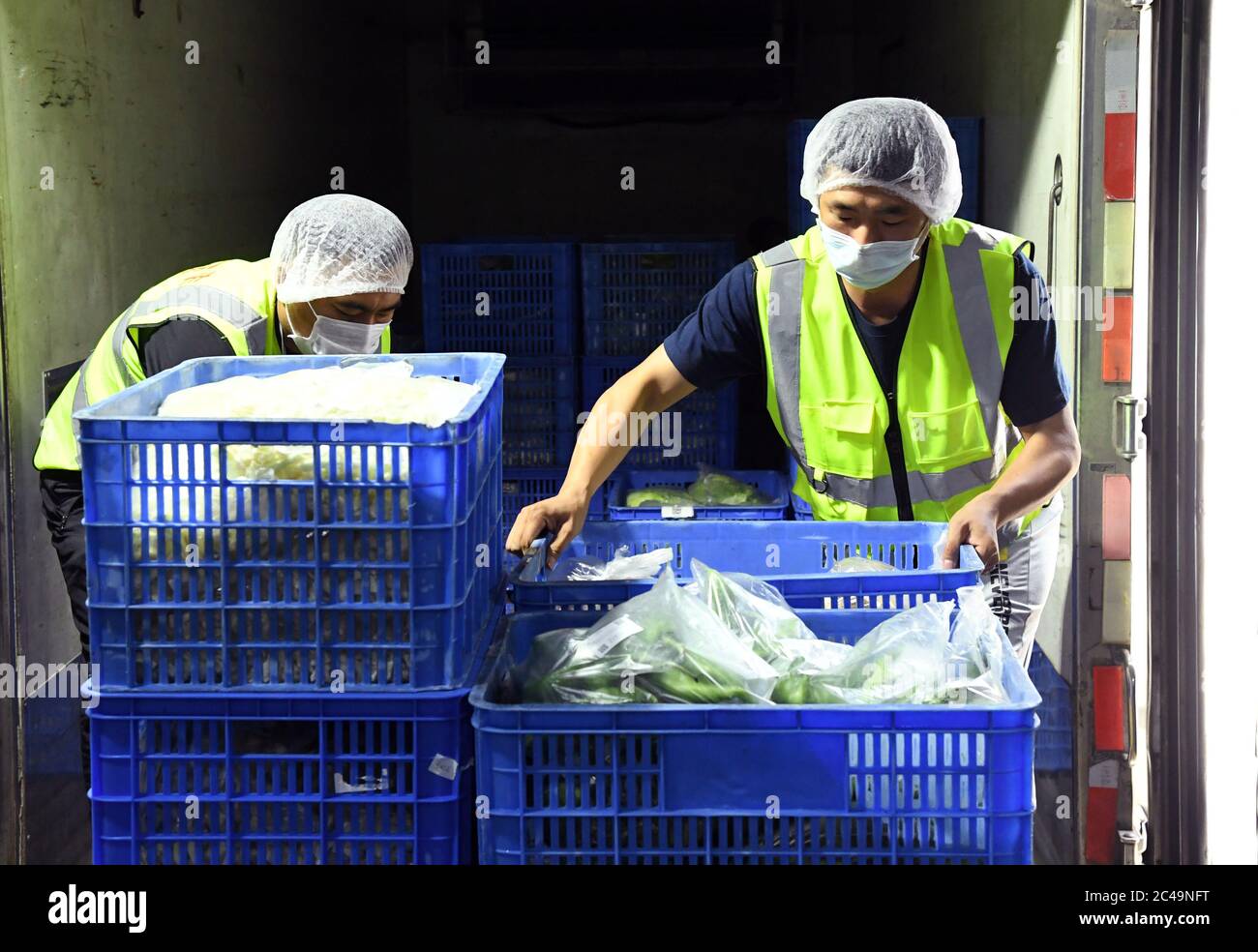 (200625) -- PECHINO, 25 giugno 2020 (Xinhua) -- personale trasferiscono verdure al magazzino di conservazione di Pinggu Mafang trasferimento di deposito e stazione di trasporto per frutta e verdura che entrano a Pechino nel distretto di Pinggu, Pechino, capitale della Cina, 25 giugno 2020. La stazione di stoccaggio e trasporto dei trasferimenti, che comprende l'area di disinfezione, l'area di turnover, l'area di stoccaggio temporaneo e l'area di gestione chiusa, è stata recentemente messa in uso. La capacità di trasporto dei camion può raggiungere oltre 50 veicoli e il volume di transito giornaliero di frutta e verdura può raggiungere più di 1,000 t. Foto Stock