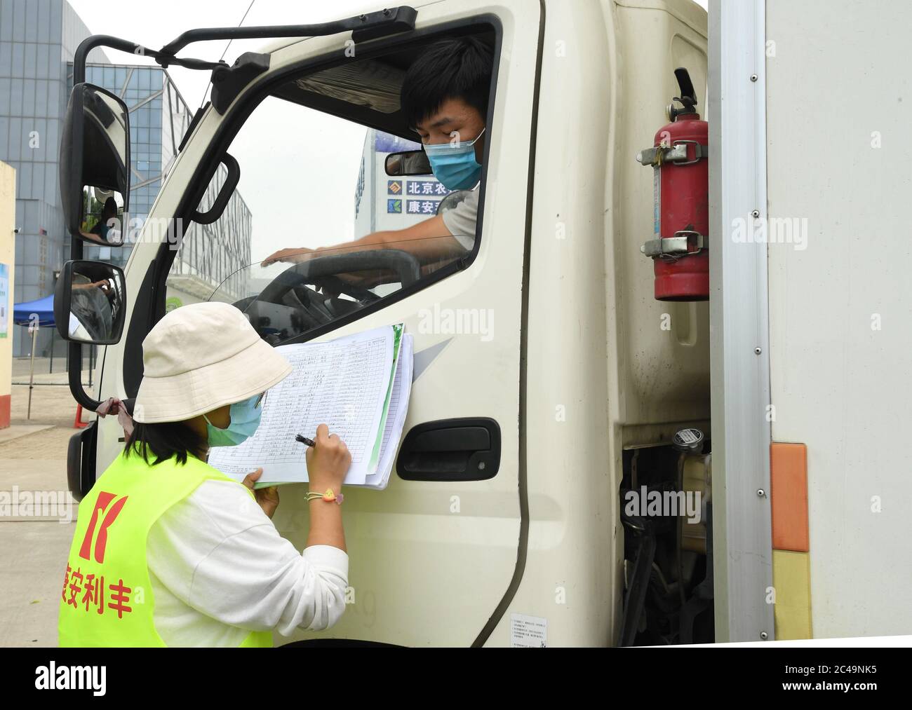 (200625) -- PECHINO, 25 giugno 2020 (Xinhua) -- UN membro dello staff registra le informazioni di un conducente di camion e del suo veicolo all'entrata del Pinggu Mafang trasferimento di stoccaggio e stazione di trasporto per frutta e verdura che entra a Pechino nel distretto di Pinggu, Pechino, capitale della Cina, 25 giugno 2020. La stazione di stoccaggio e trasporto dei trasferimenti, che comprende l'area di disinfezione, l'area di turnover, l'area di stoccaggio temporaneo e l'area di gestione chiusa, è stata recentemente messa in uso. La capacità di trasporto dei camion qui può raggiungere più di 50 veicoli, e il volume di transito giornaliero di frutta e. Foto Stock