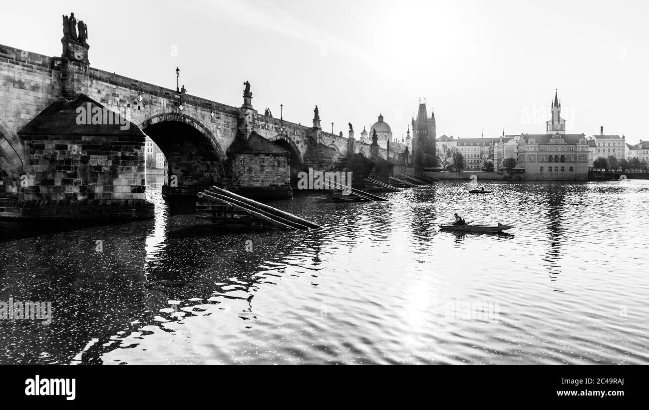 Pesca sotto il Ponte Carlo, ceco: Karluv Most. Mattina soleggiata sul fiume Moldava. Praga, Repubblica Ceca. Immagine in bianco e nero. Foto Stock