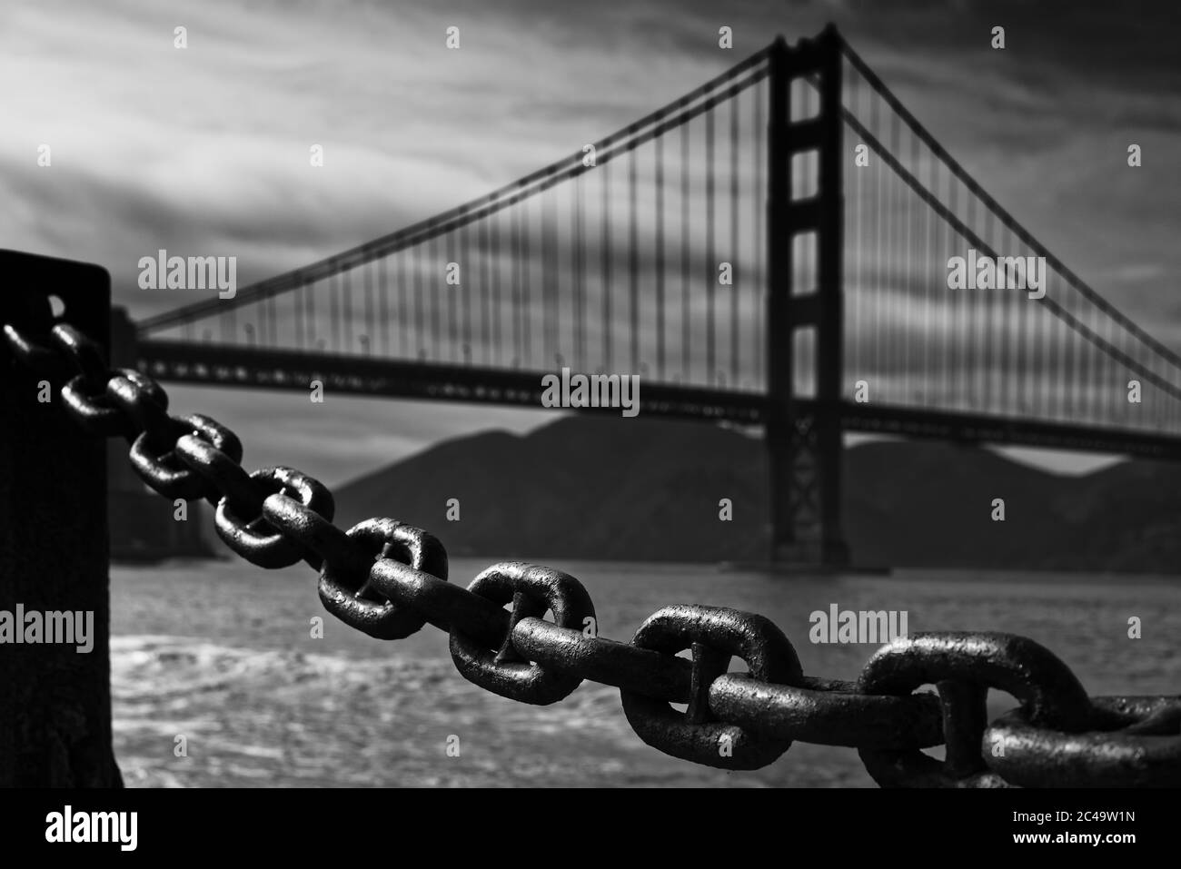 La luce della sera giocava con una grande catena, che viene usata come recinzione. Sullo sfondo c'è la silhouette del Golden Gate Bridge. Foto Stock
