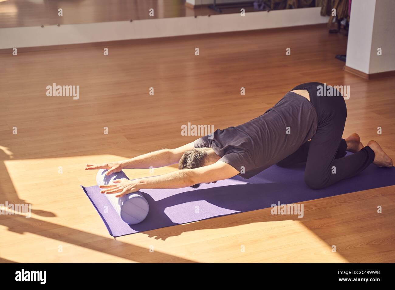 Giovane uomo che fa esercizio con blocco a rulli yoga Foto Stock