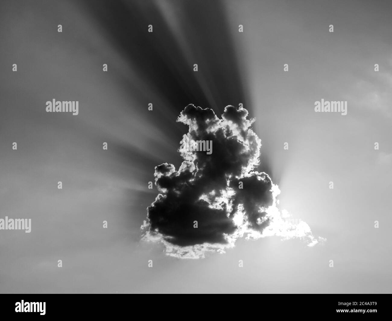Il sole si nuvola dal sole serale dietro una nuvola piccola. Immagine in bianco e nero. Foto Stock