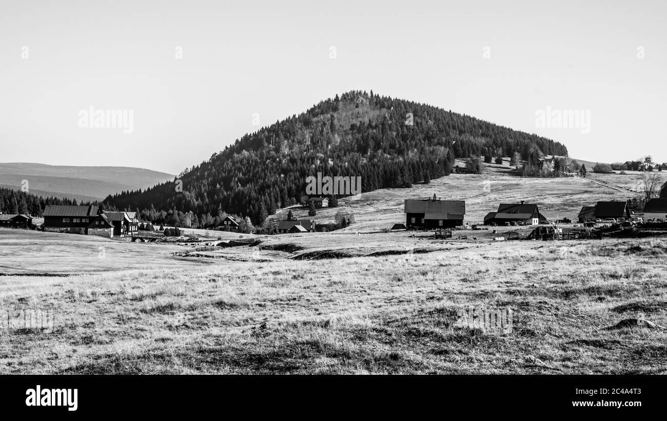 Monte Bukovec sopra il Villaggio di Jizerka nelle Montagne di Jizera, Repubblica Ceca. Giornata di sole. Immagine in bianco e nero. Foto Stock