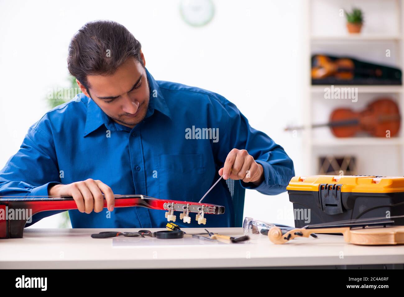 Giovane uomo riparatore riparando la chitarra Foto Stock