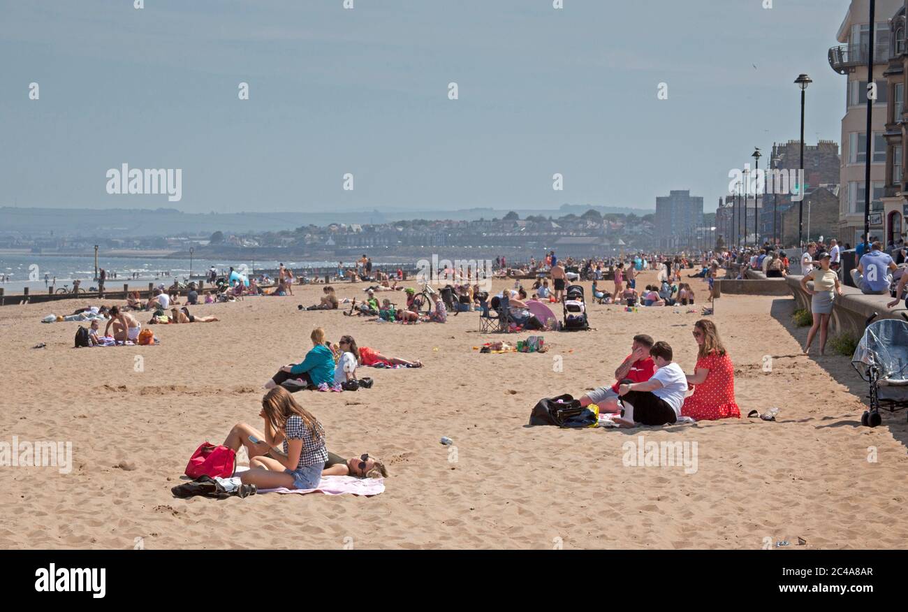 Portobello, Edimburgo, Scozia, Regno Unito. 25 giugno 2020. 2° giorno di tempo molto caldo anche se più fresco per iniziare con una brezza fresca come ha cominciato a riscaldare vapore ha cominciato a salire dalla sabbia bagnata causando una foschia, temperatura ha raggiunto 20 gradi all'ora di pranzo, più persone fuori prima di là erano ieri, Luppolyusing schermo solare per proteggerli dai raggi UV più alti che gli agenti atmosferici stanno avvertendo circa. Foto Stock