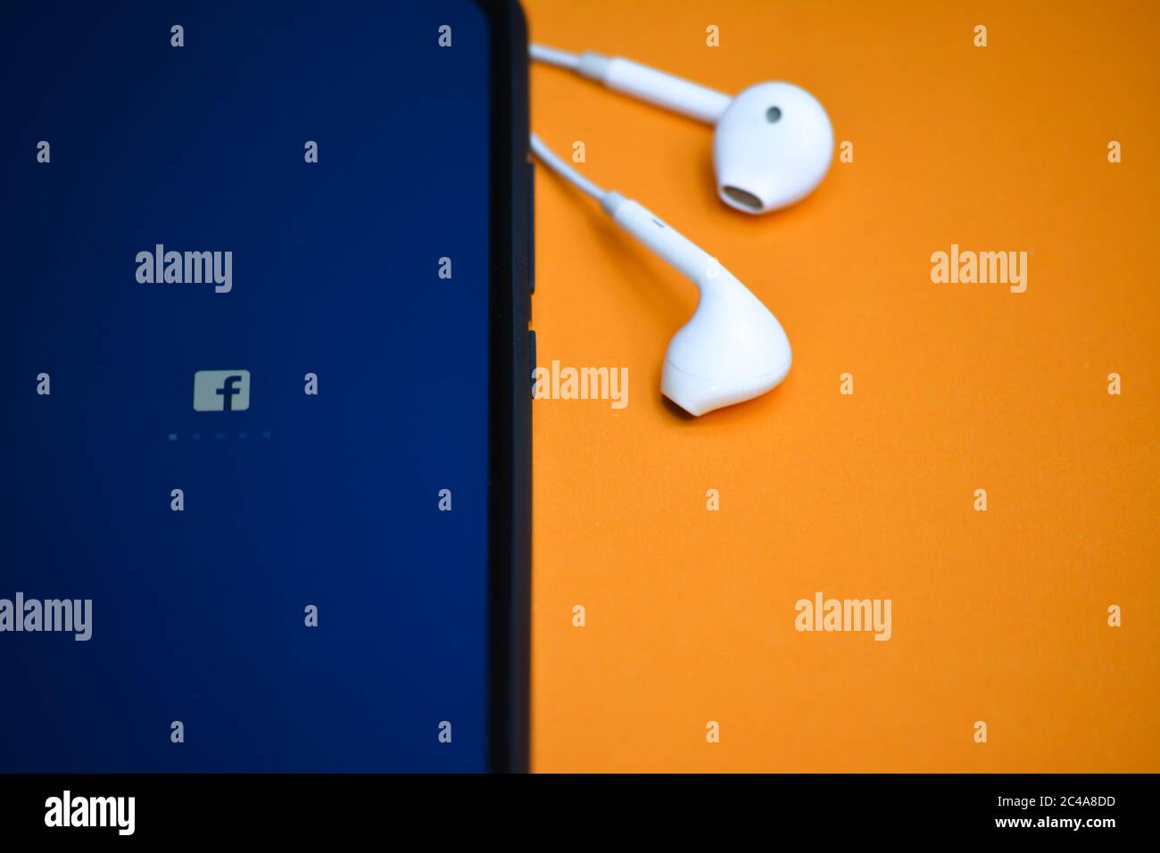 TIKAMGARH, MADHYA PRADESH, INDIA - 17 DICEMBRE 2019: Caricamento delle applicazioni Facebook sullo schermo del telefono cellulare con auricolari. Foto Stock