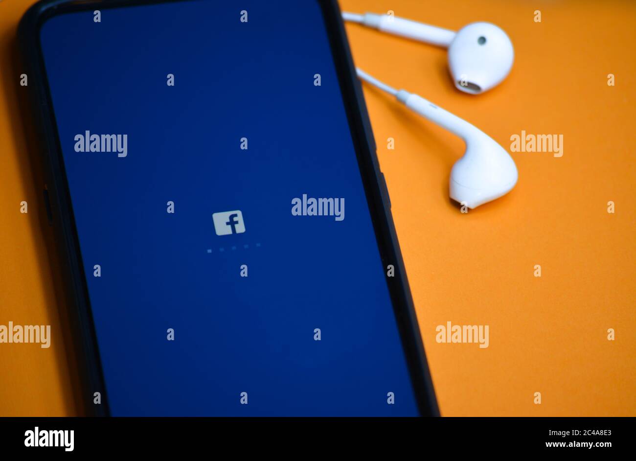 TIKAMGARH, MADHYA PRADESH, INDIA - 17 DICEMBRE 2019: Caricamento delle applicazioni Facebook sullo schermo del telefono cellulare con auricolari. Foto Stock