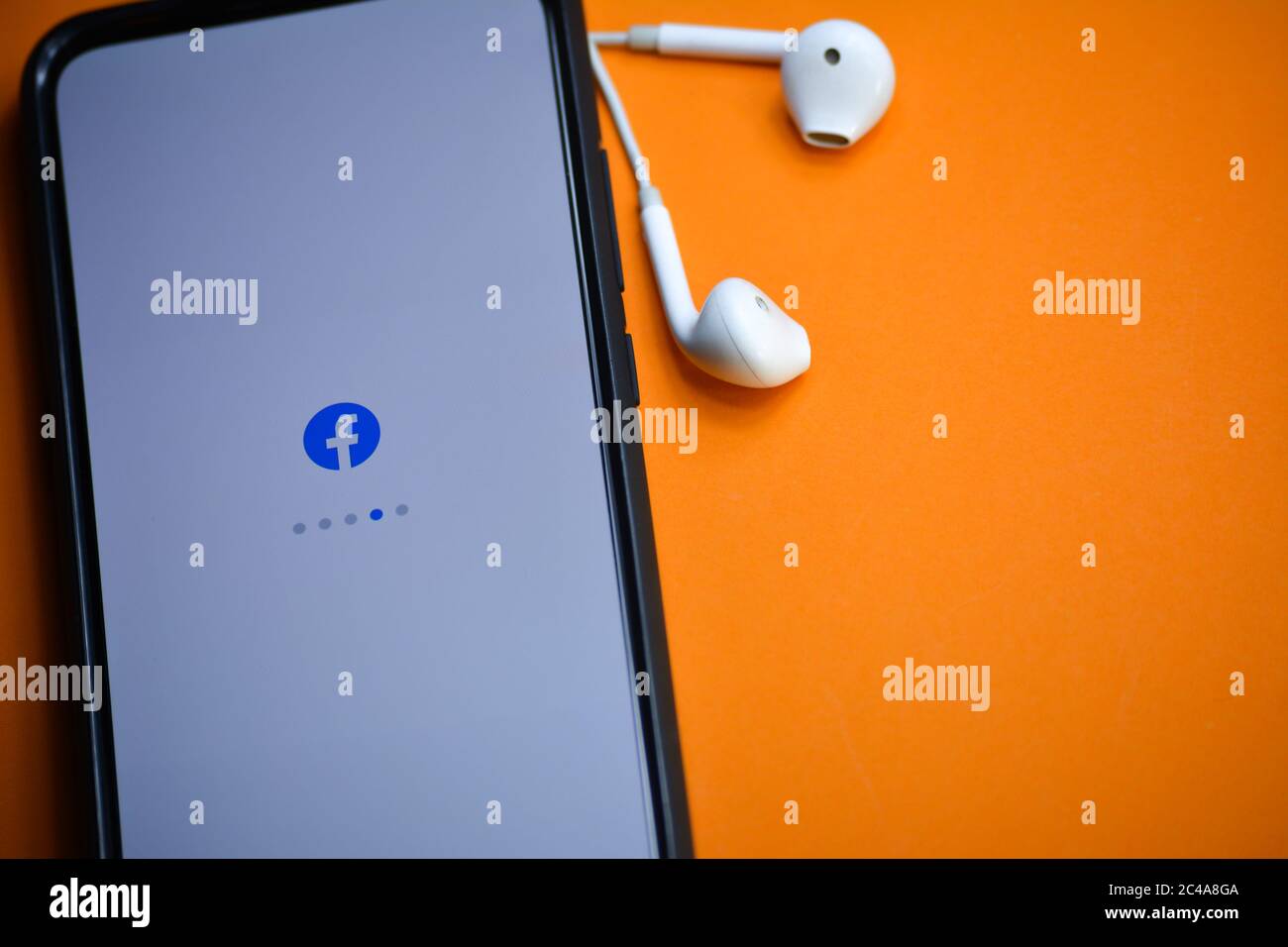 TIKAMGARH, MADHYA PRADESH, INDIA - 17 DICEMBRE 2019: Caricamento delle applicazioni Facebook sullo schermo del telefono cellulare con auricolari. Foto Stock