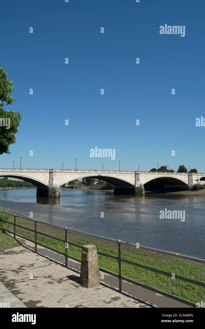 In primo piano, un blocco di cemento contrassegnato ubr che indica il punto finale della corsa universitaria in barca; sullo sfondo, chiswick ponte Foto Stock