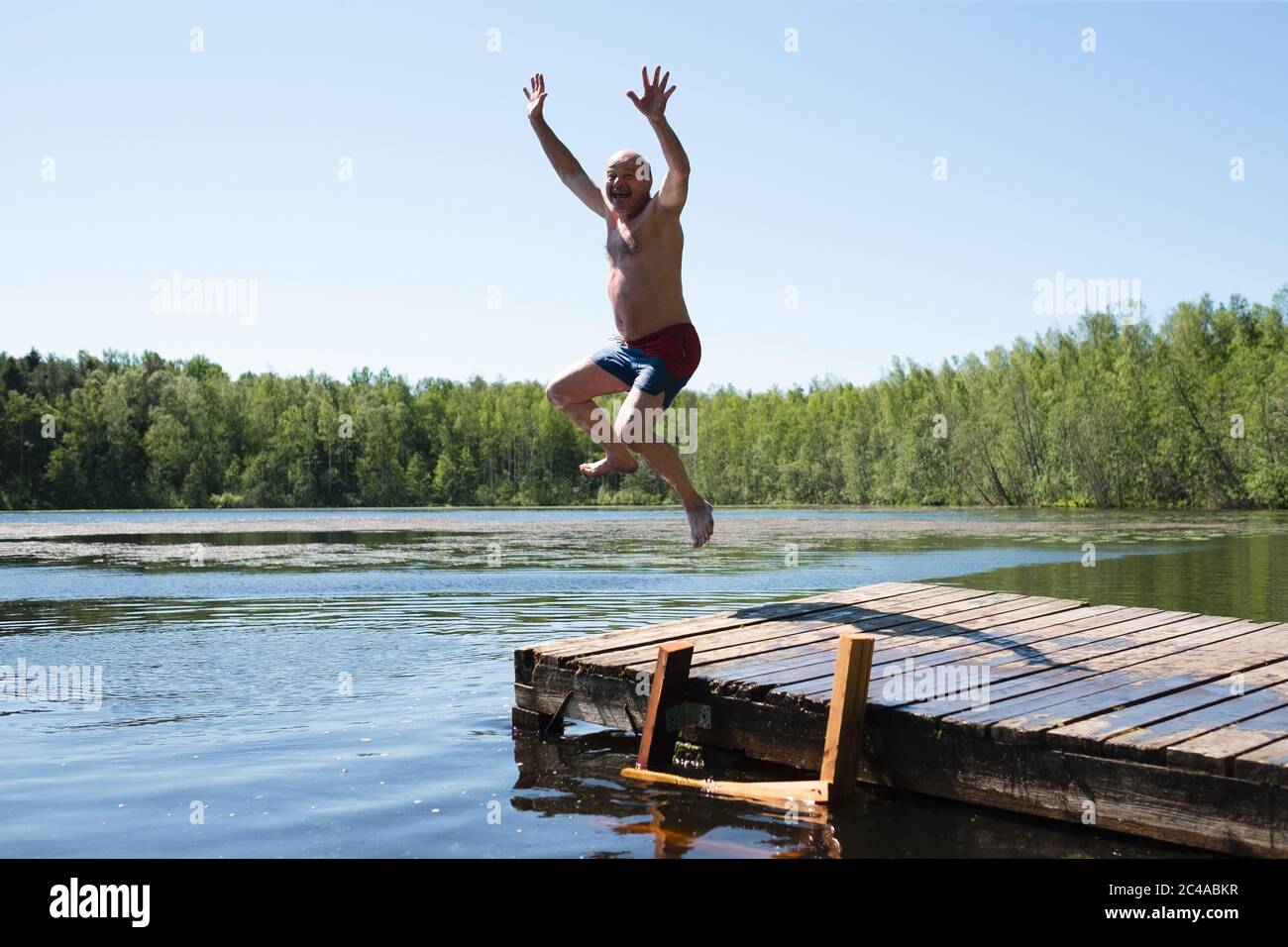 L'uomo salta all'acqua del lago divertendosi durante la vacanza. Foto Stock