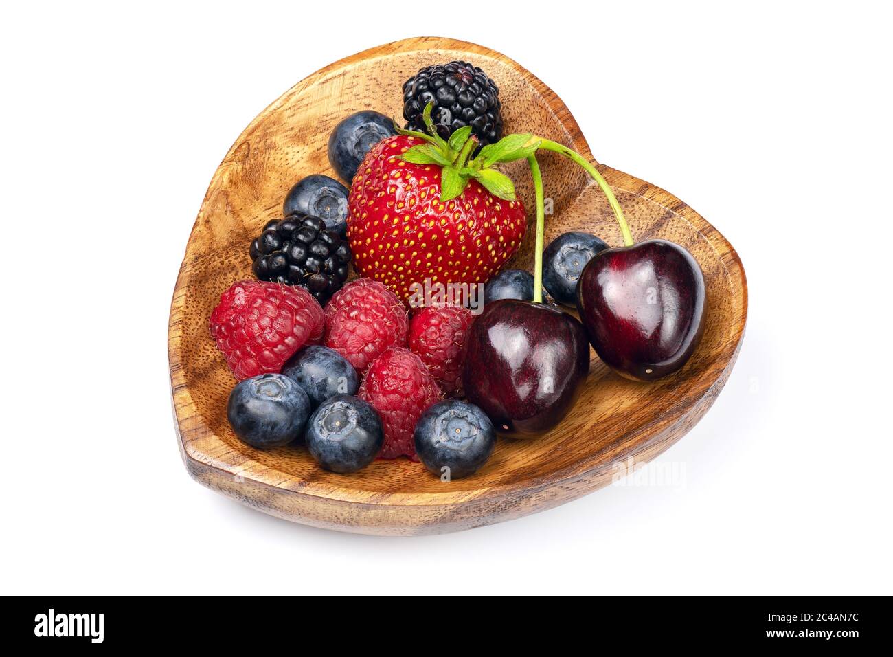 Bacche diverse fresche in ciotola di legno a forma di cuore isolato su sfondo bianco. Profondità di campo completa con tracciato di ritaglio. Foto Stock