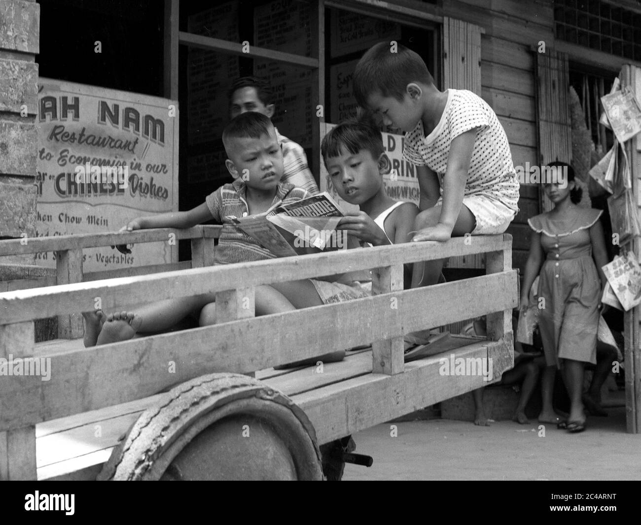 Ragazzi giovani che leggono il libro comico di Cheyenne 1959 scena di strada , Filippine Foto Stock