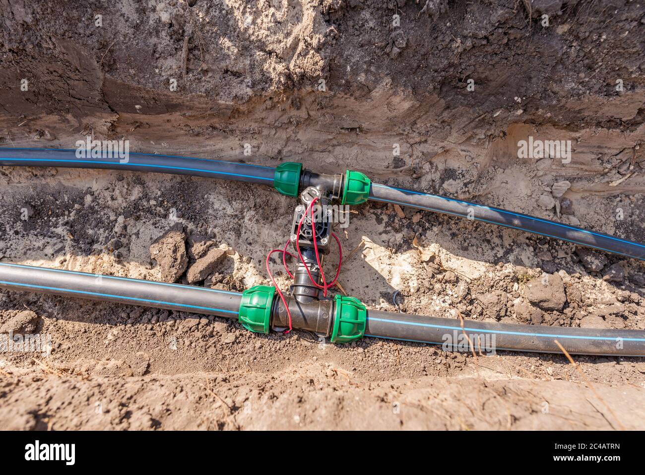 Tubi dell'acqua (tubi) e valvole di controllo per sistema di irrigazione poste in una trincea nel terreno di un parco Foto Stock
