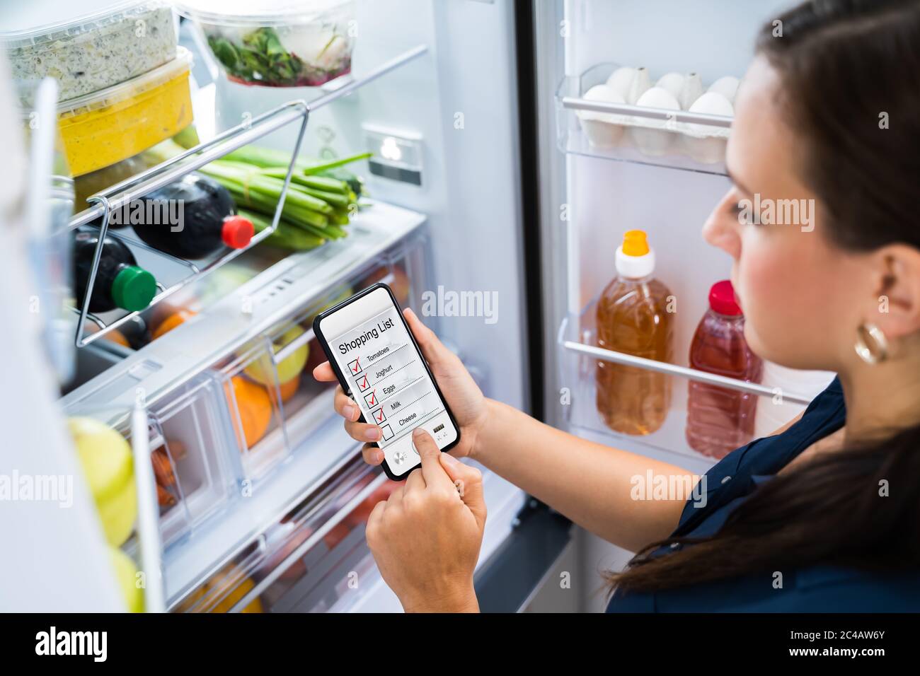 Comoda lista di negozi di alimentari, app per telefono vicino al frigorifero Foto Stock